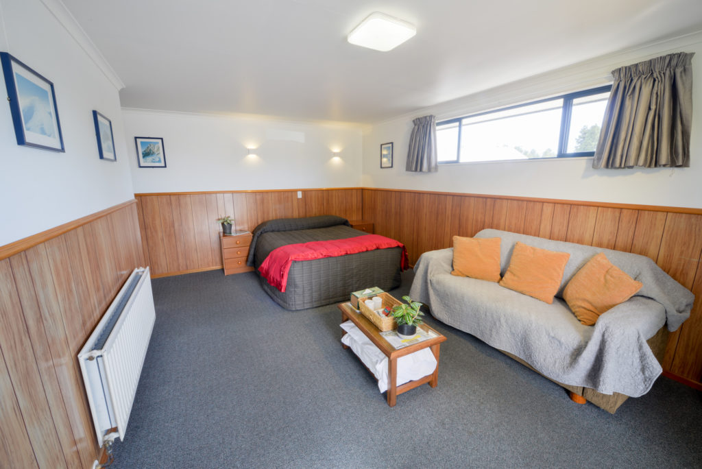 Queen size bed with sofa in motel wilderness haast new zealand